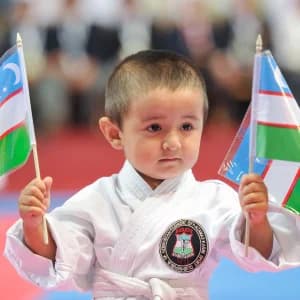 O‘zbekiston bayroqlarini ushlab turgan yosh karatechi