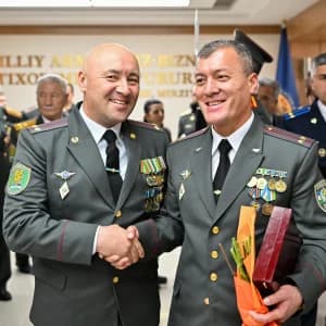 Harbiy xizmatchilar binoda qoʻl siqishmoqda