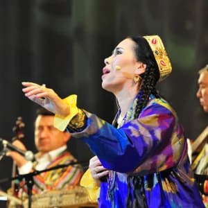 Anʼanaviy libosdagi ijrochi sahnada qoʻshiq kuylaydi