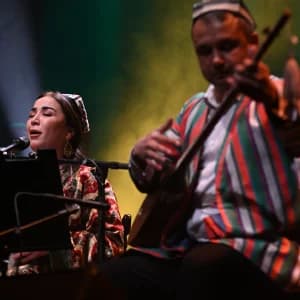 Anʼanaviy libosdagi ijrochilar sahnada musiqa ijro etadilar.