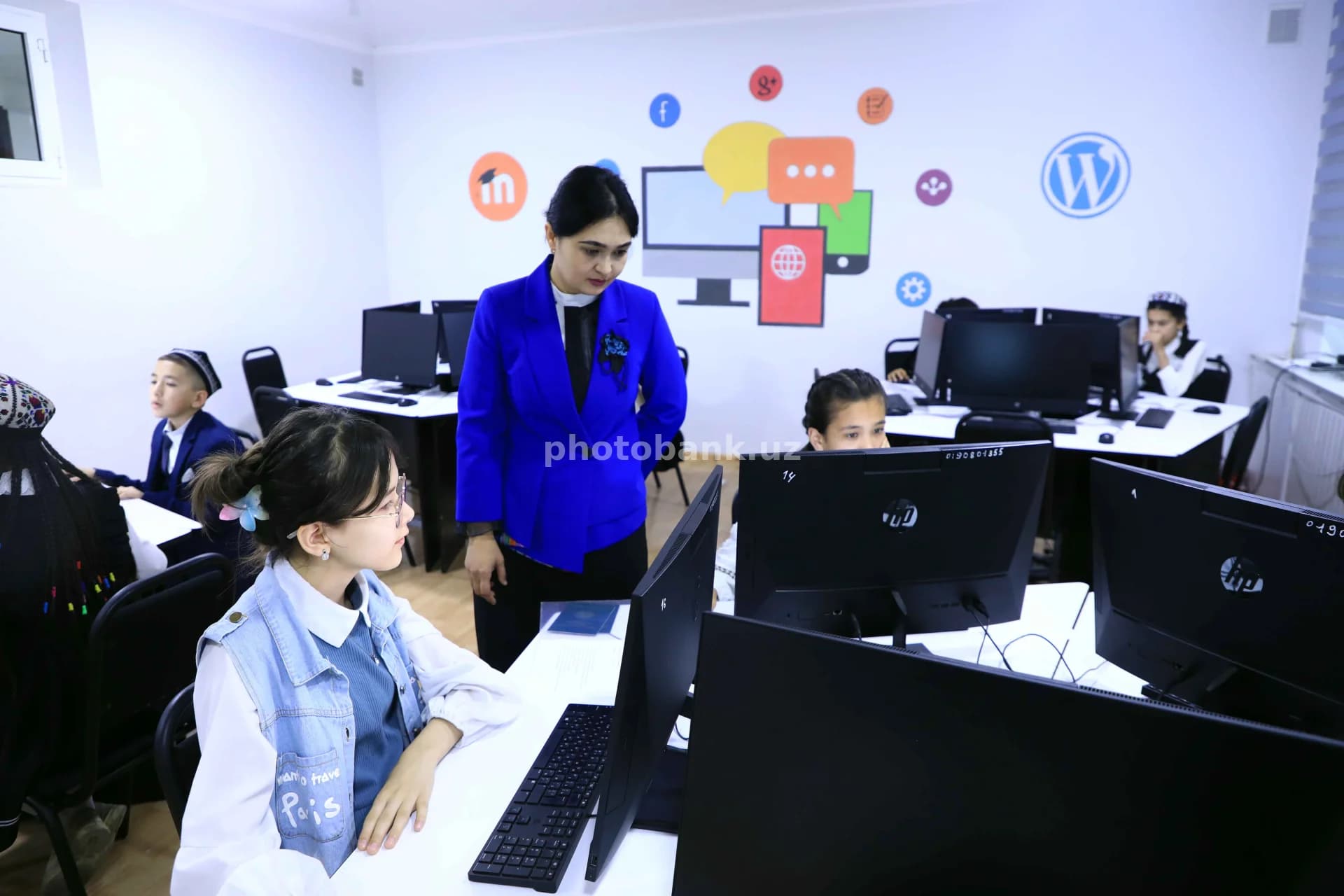 O‘qituvchi kompyuter laboratoriyasida o‘quvchilarga rahbarlik qiladi