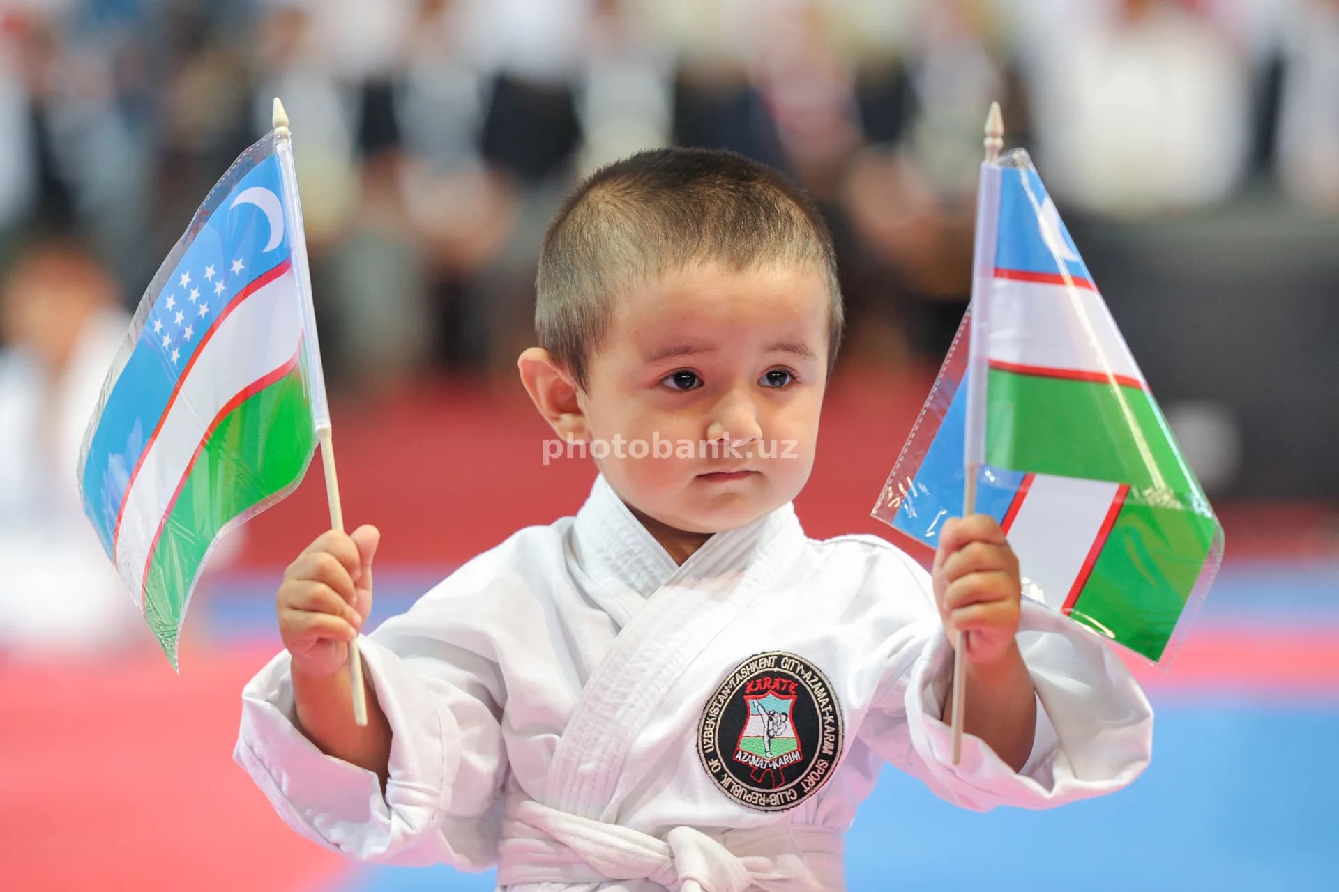 O‘zbekiston bayroqlarini ushlab turgan yosh karatechi