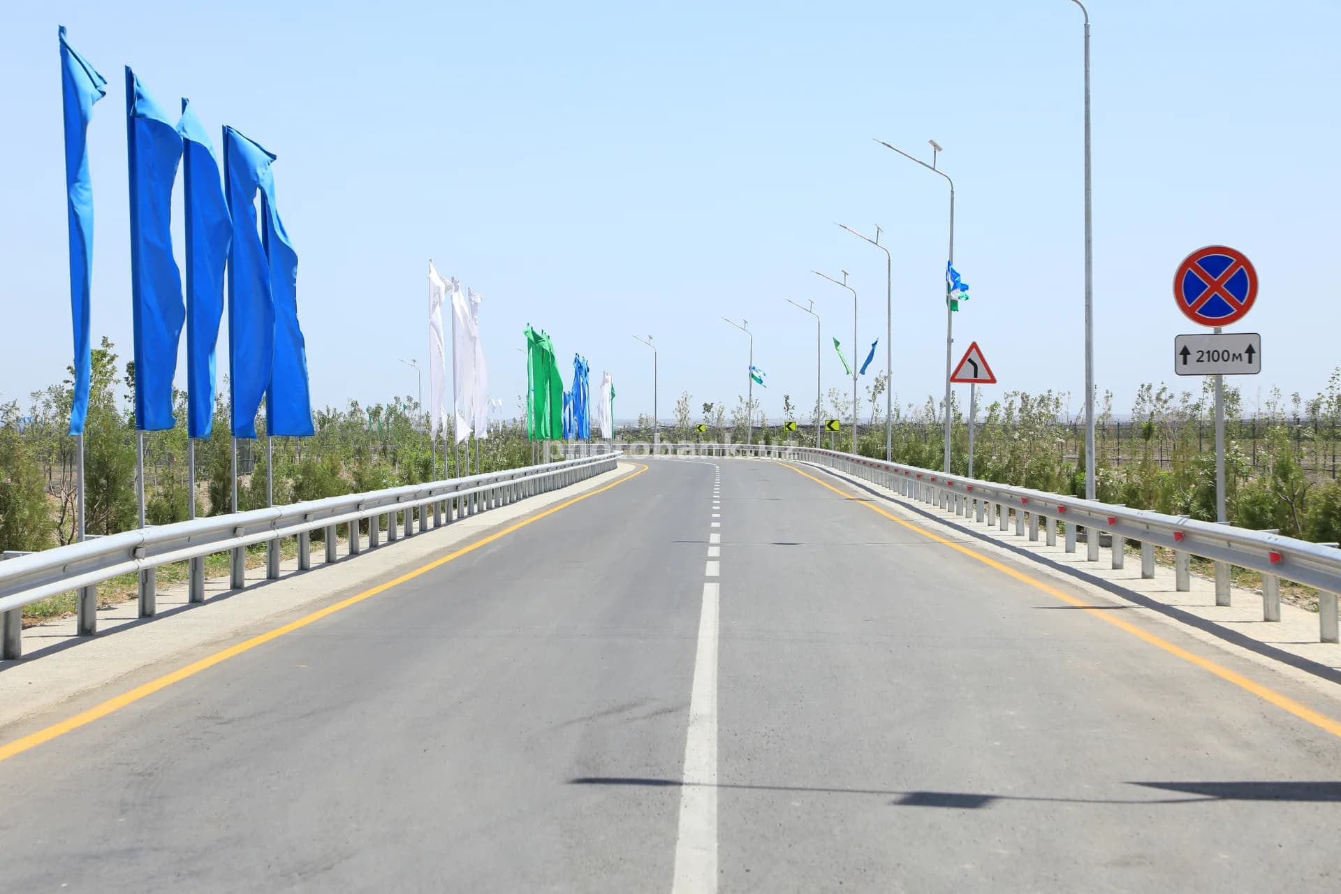 Dekorativ bayroqlar bilan bezatilgan asfalt avtomobil yo‘li