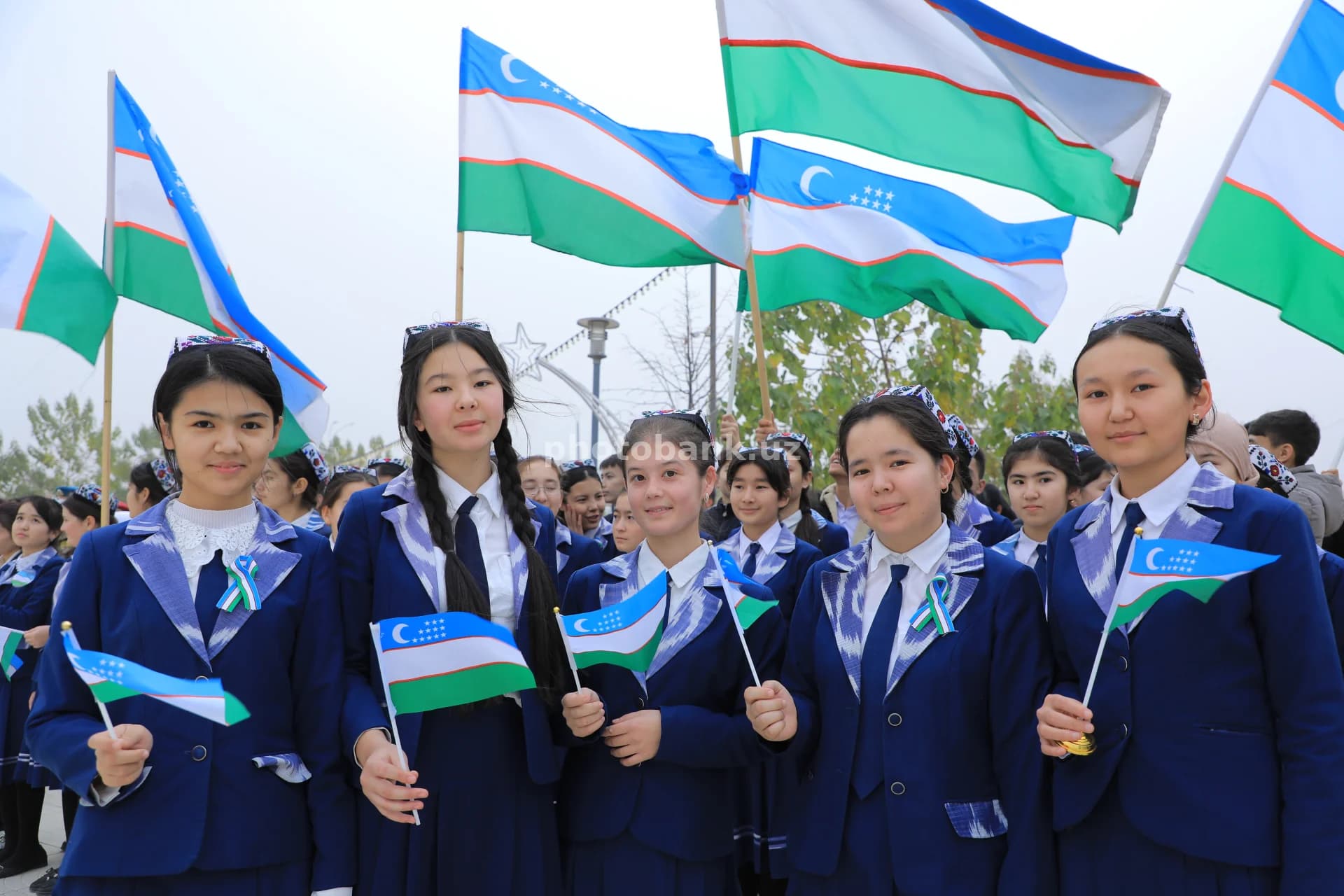 Учащиеся празднуют с государственными флагами Узбекистана
