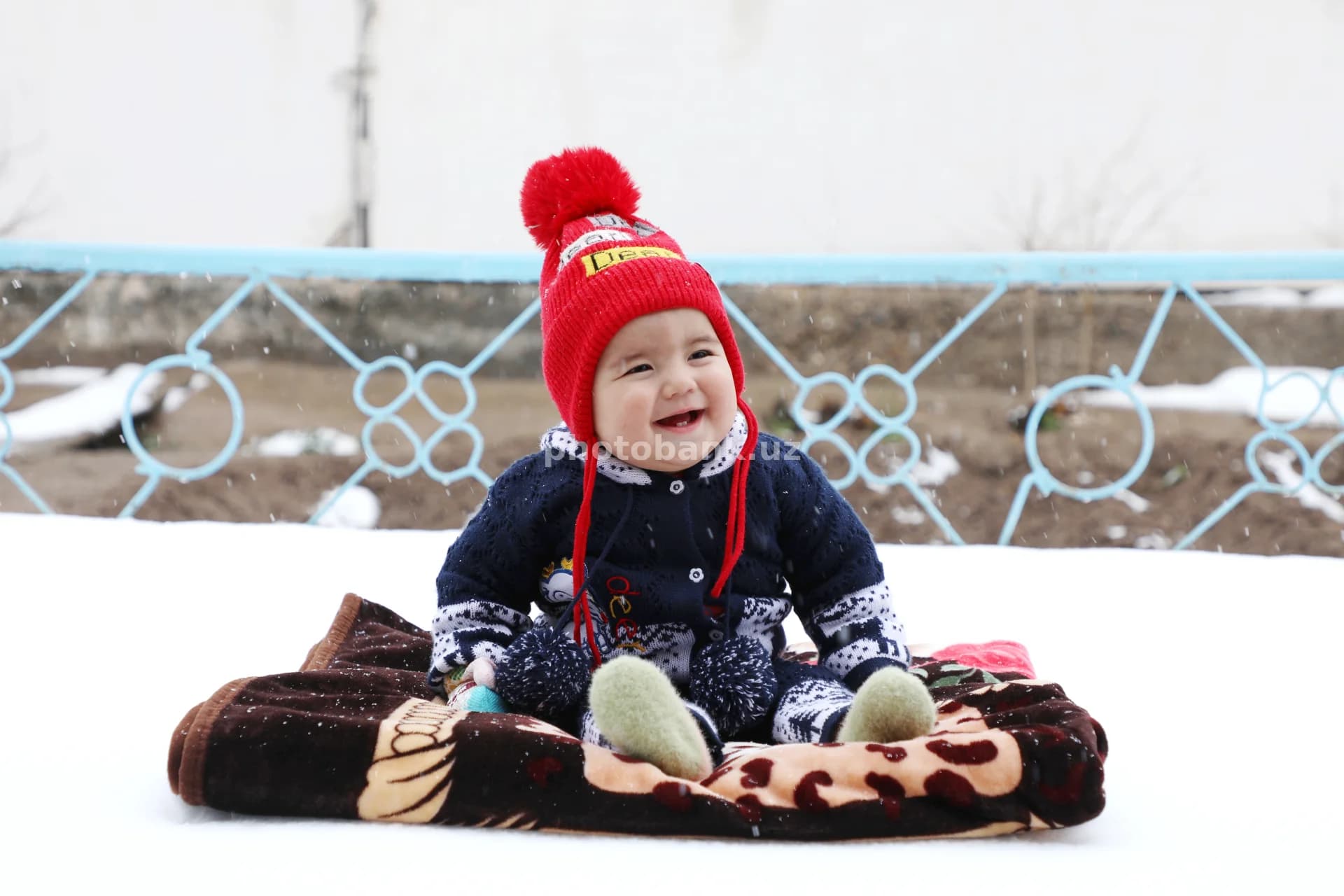 Qorli yerda o‘tirgan tabassumli chaqaloq