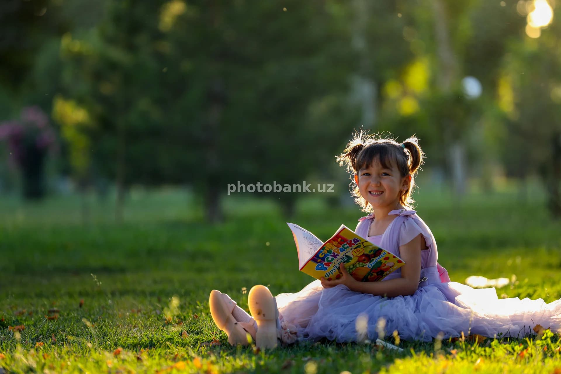 Yosh qiz bog‘da kitob o‘qimoqda