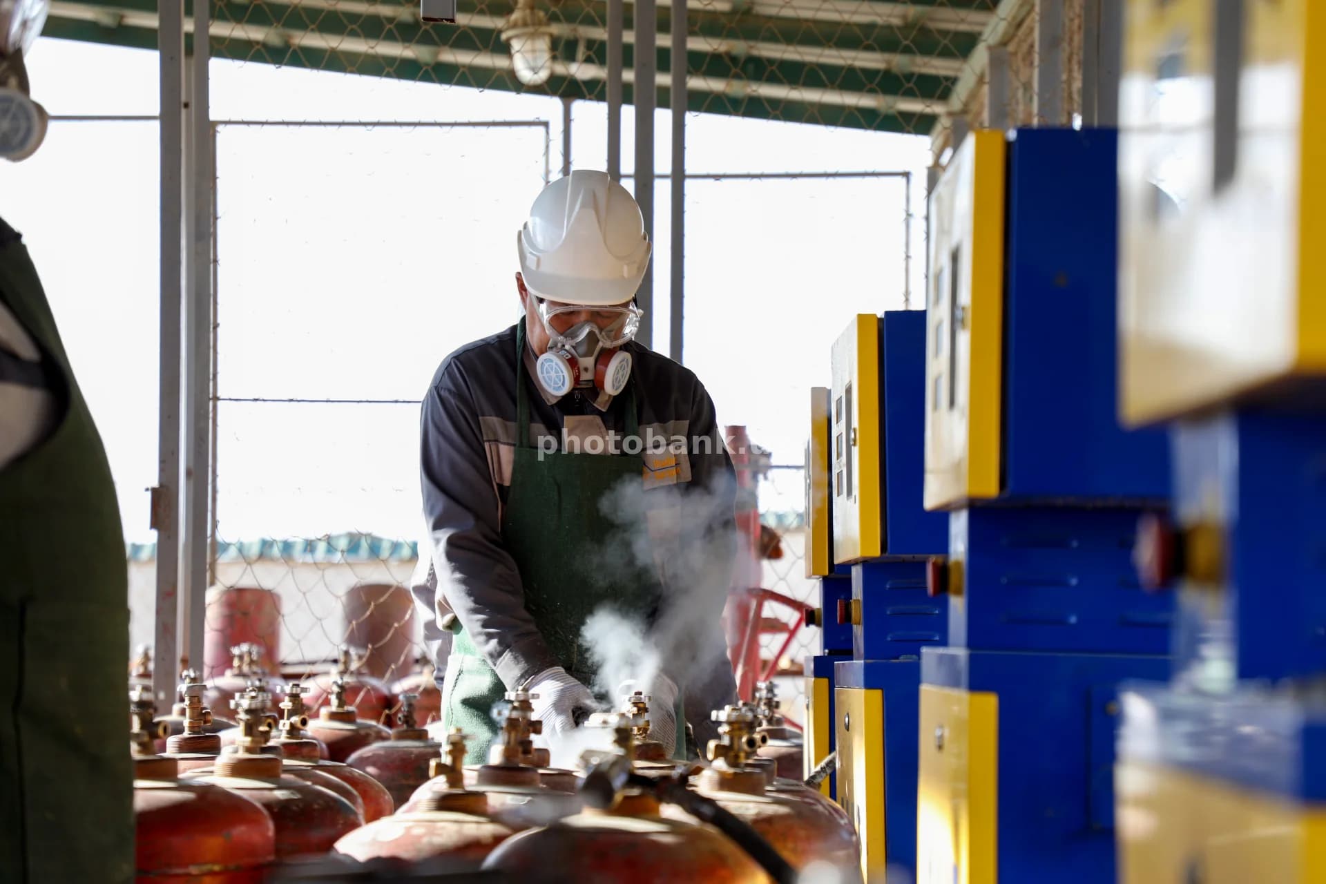 работник, заправляющий газовые баллоны на открытом воздухе