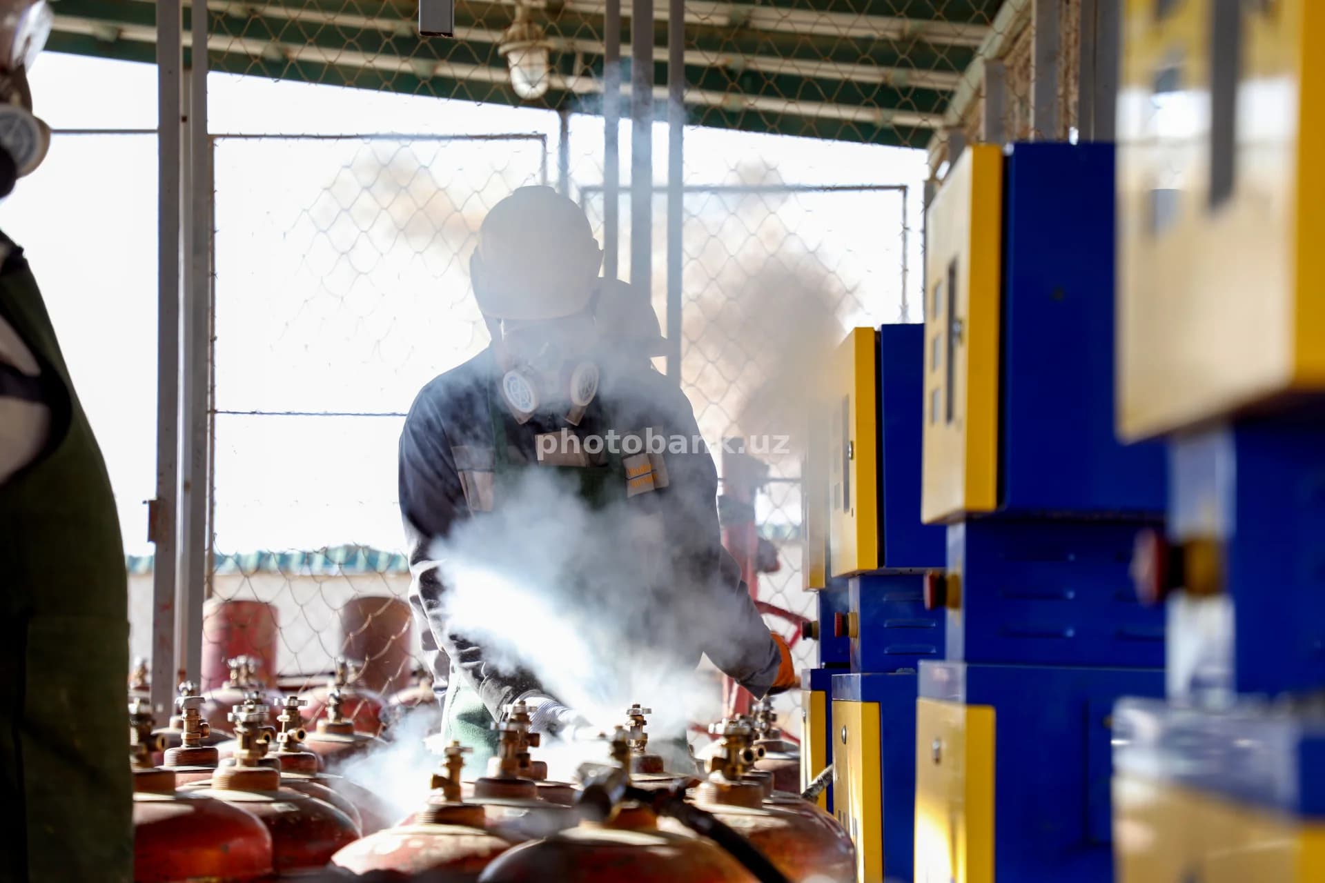работник, заправляющий газовые баллоны на открытом воздухе