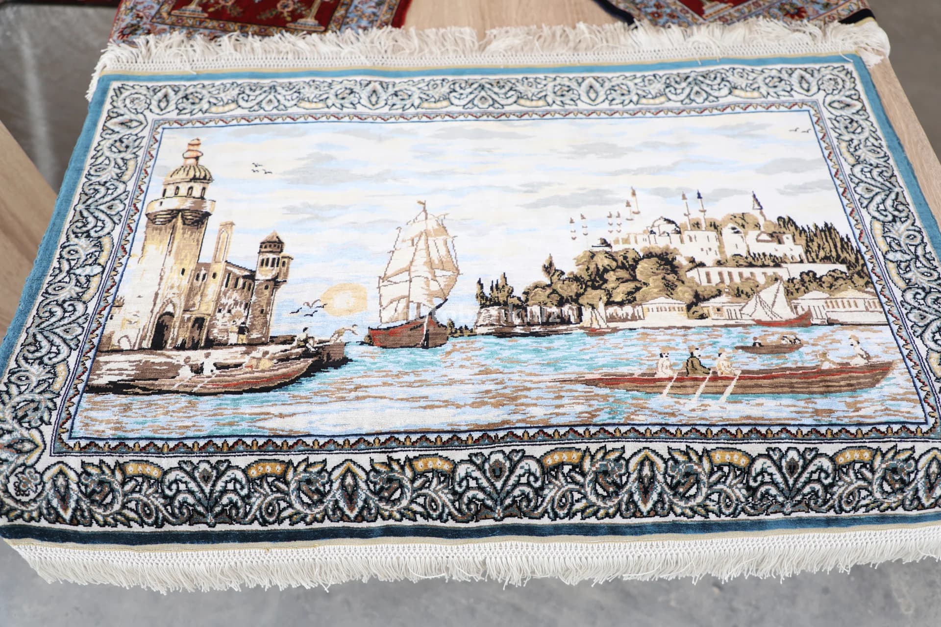 To‘qima gilamda qirg‘oq manzarasi tasvirlangan.