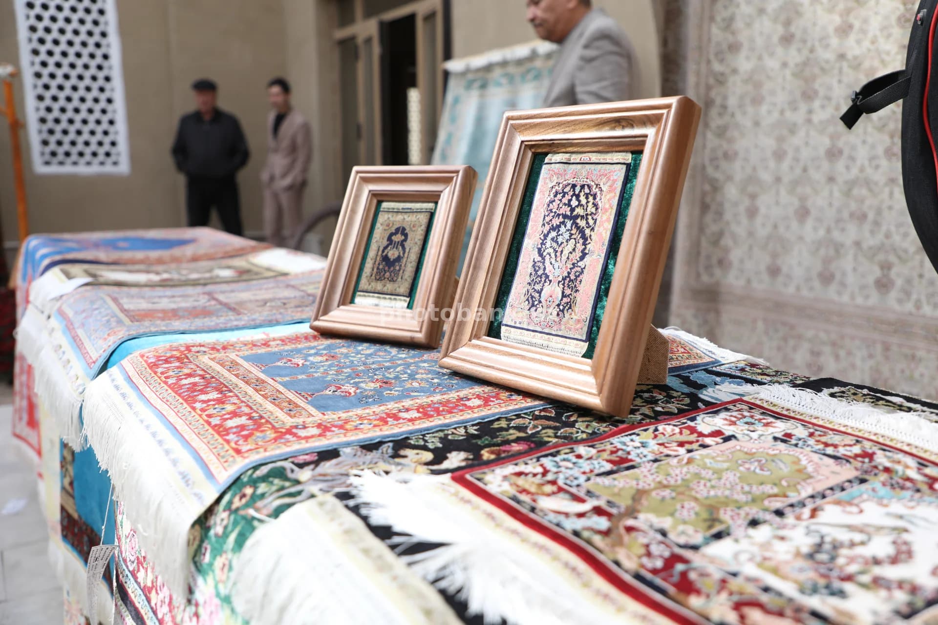 Hunarmand miniatyura to‘qilgan gilamlarni namoyish etmoqda