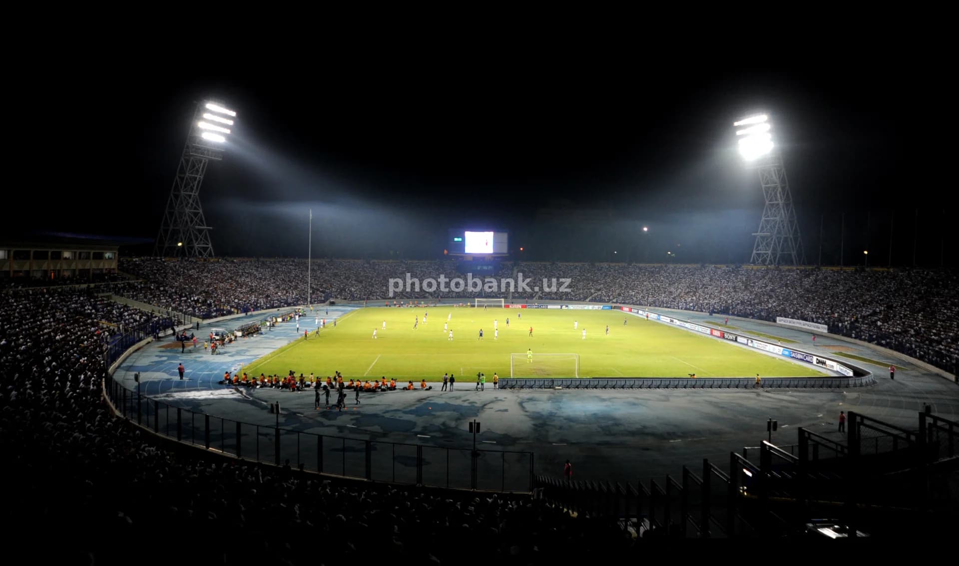Oʻyinchilar yoritilgan stadionda bellashadilar.