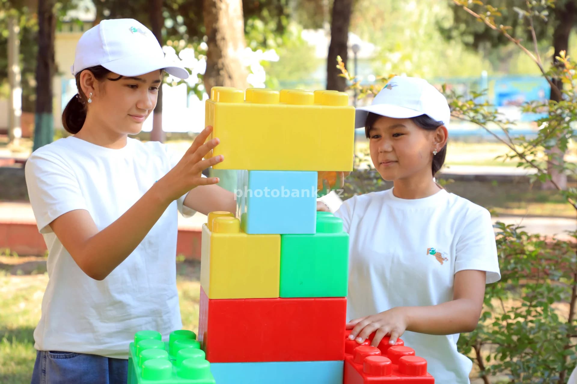two girls building plastic tower
