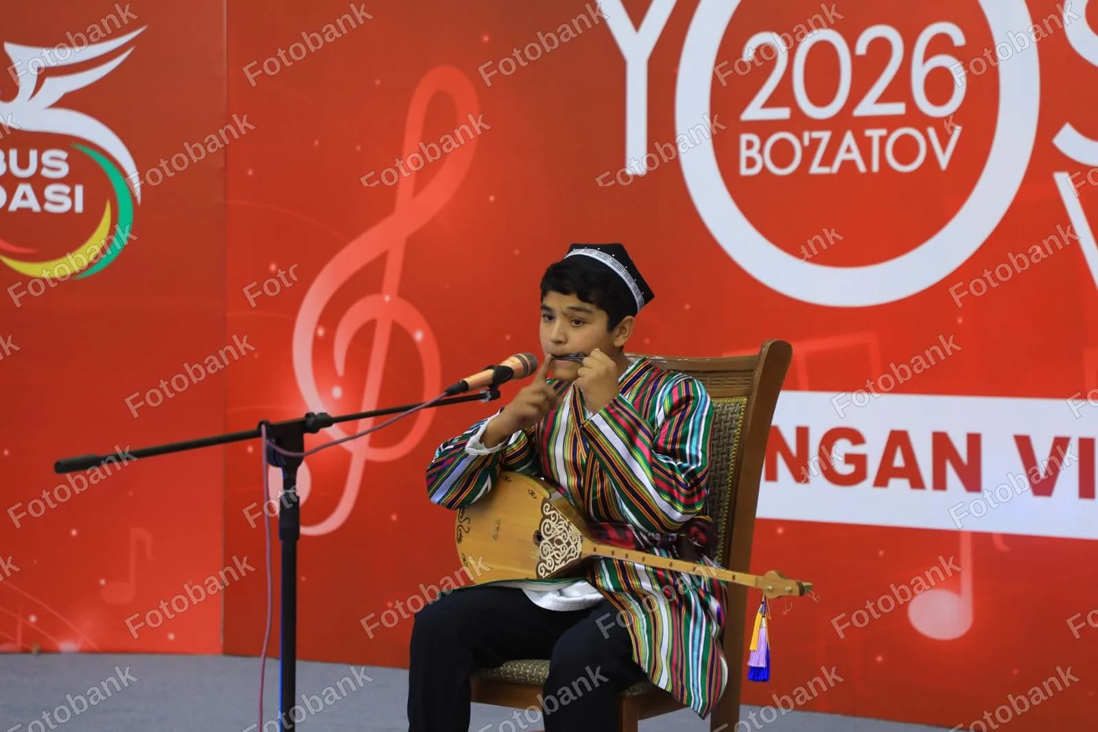 Yosh bola anʼanaviy cholgʻu asbobini chalmoqda
