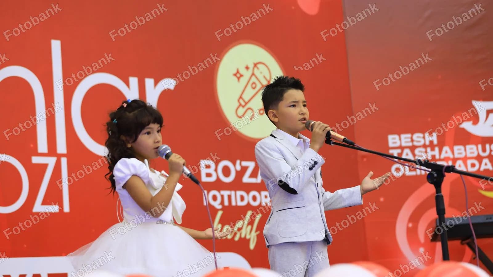 Sahnada qoʻshiq aytayotgan yosh bolalar