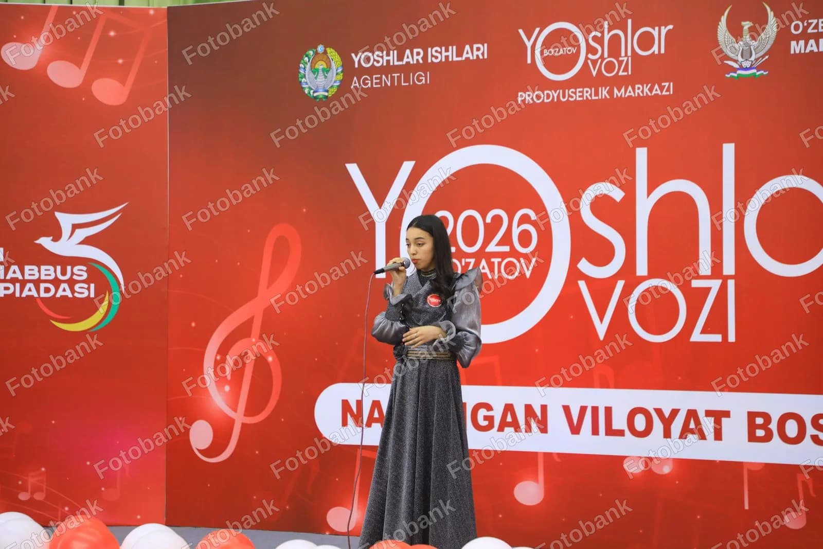 Sahnada qoʻshiq aytayotgan yosh ayol