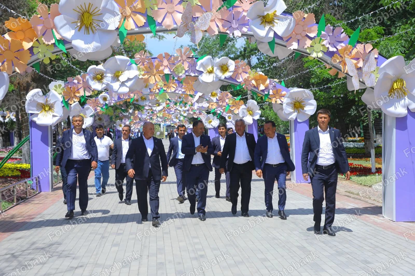 Gullar bilan bezatilgan ravoqdan oʻtayotgan amaldorlar