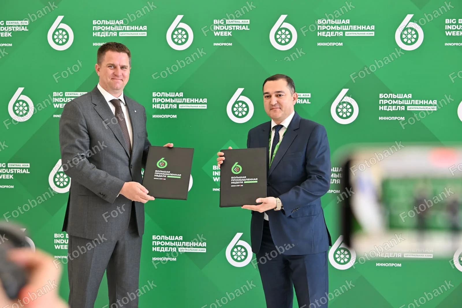 Two men holding signed documents