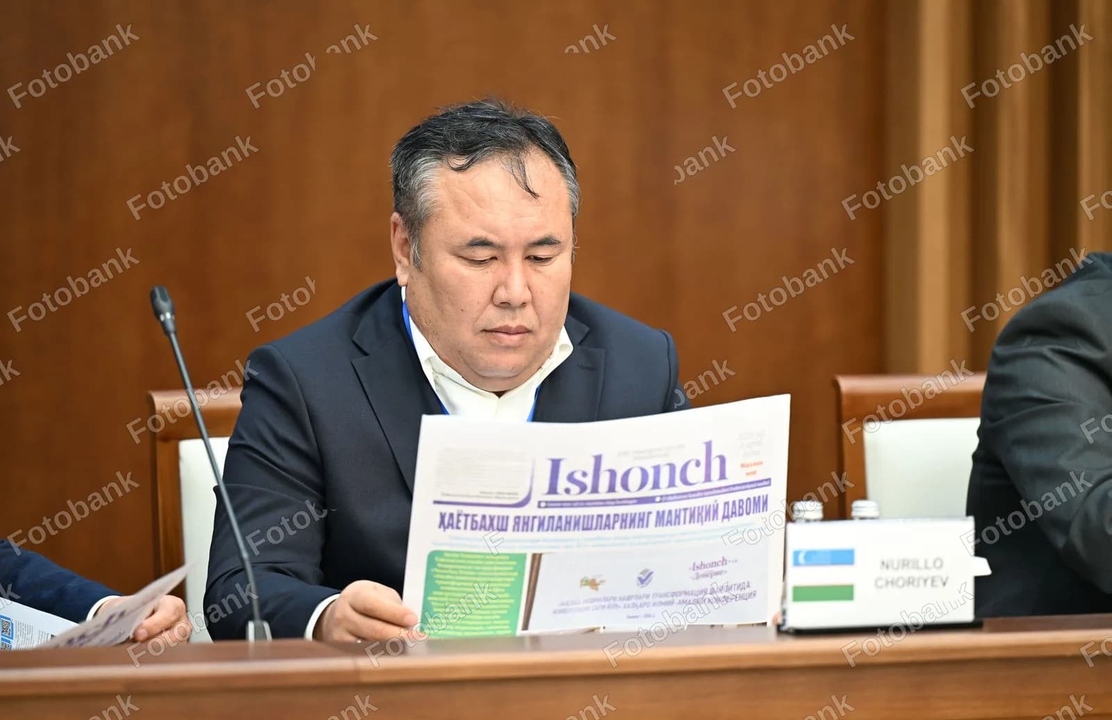 Konferensiyada gazeta oʻqiyotgan erkak