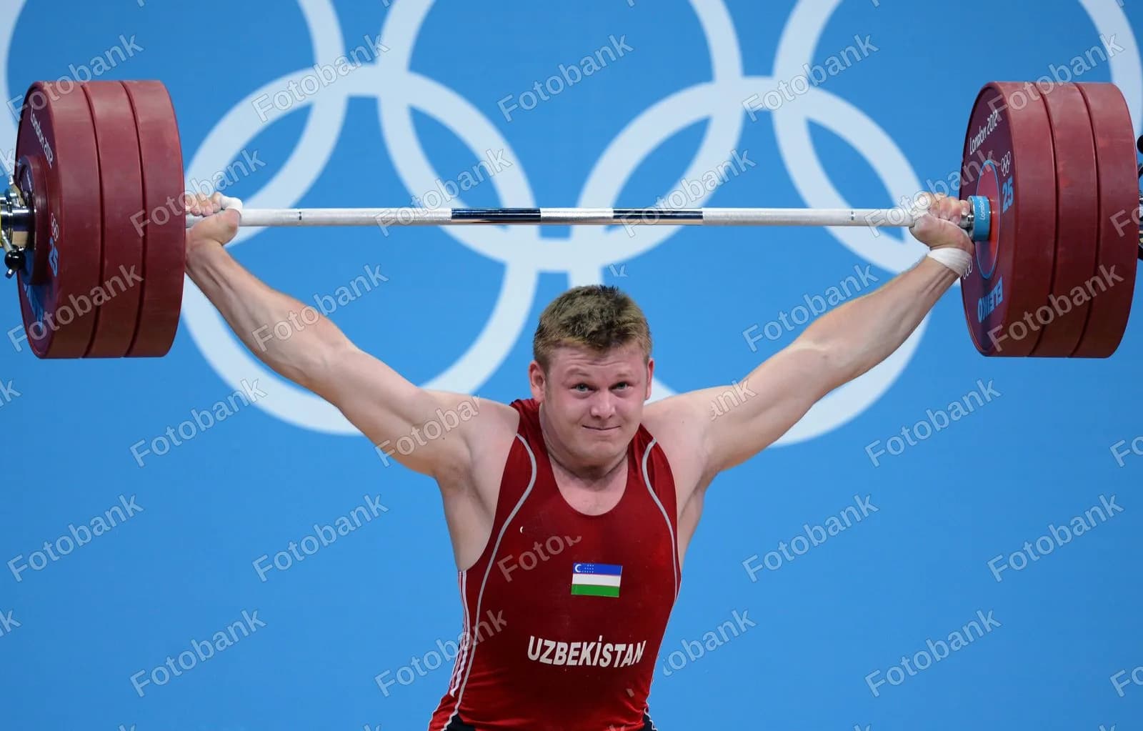Спортсмен поднимает тяжелую штангу над головой