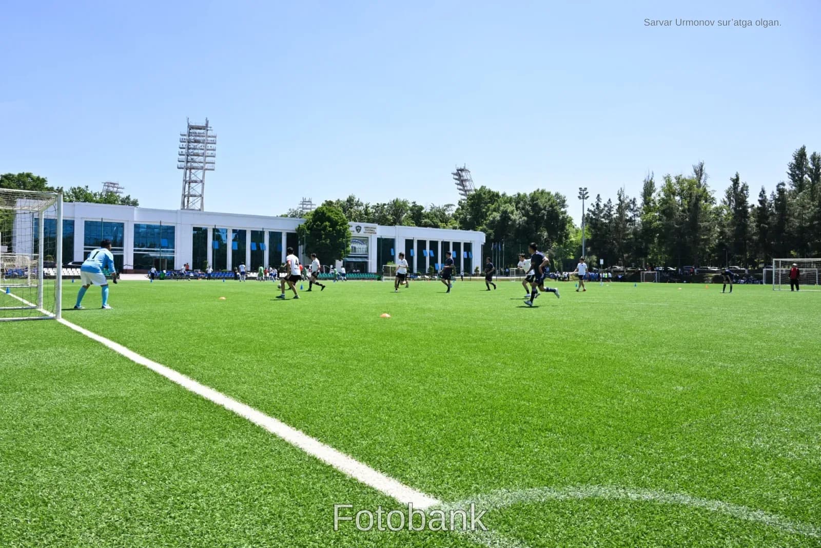Ochiq futbol maydonida oʻyinchilar shugʻullanmoqda