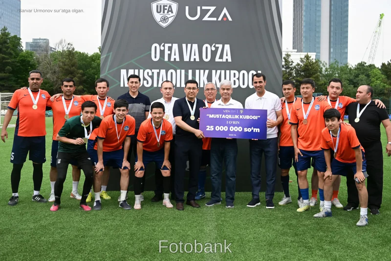 Bir guruh erkaklar sport sovrini banneri bilan suratga tushmoqda