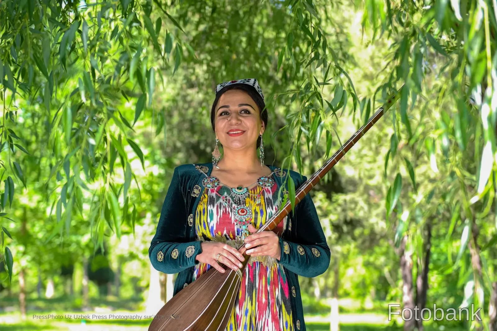 Ochiq havoda musiqa asbobini ushlab turgan anʼanaviy kiyimdagi ayol