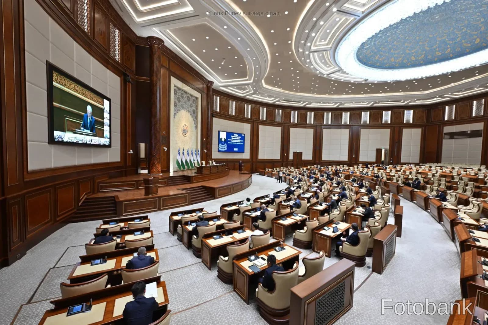 Katta auditoriya ichidagi rasmiy yigʻilishda qatnashayotgan odamlar