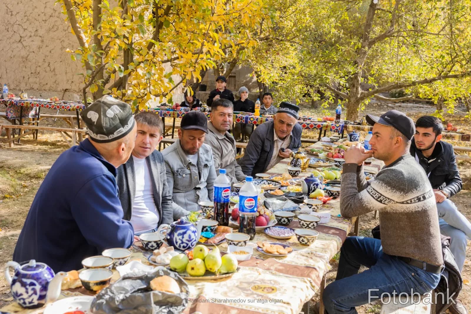 People gathered for an outdoor meal at tables set in a rural garden