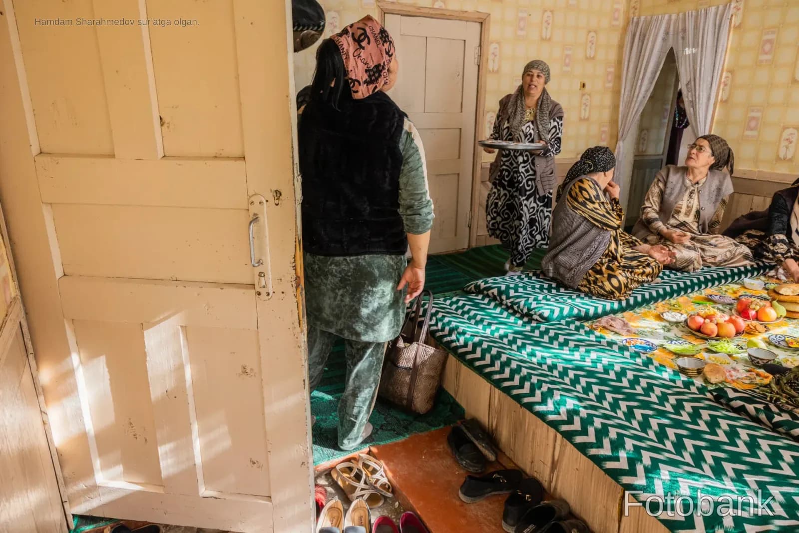 People gathered inside a room with patterned floor cushions and food