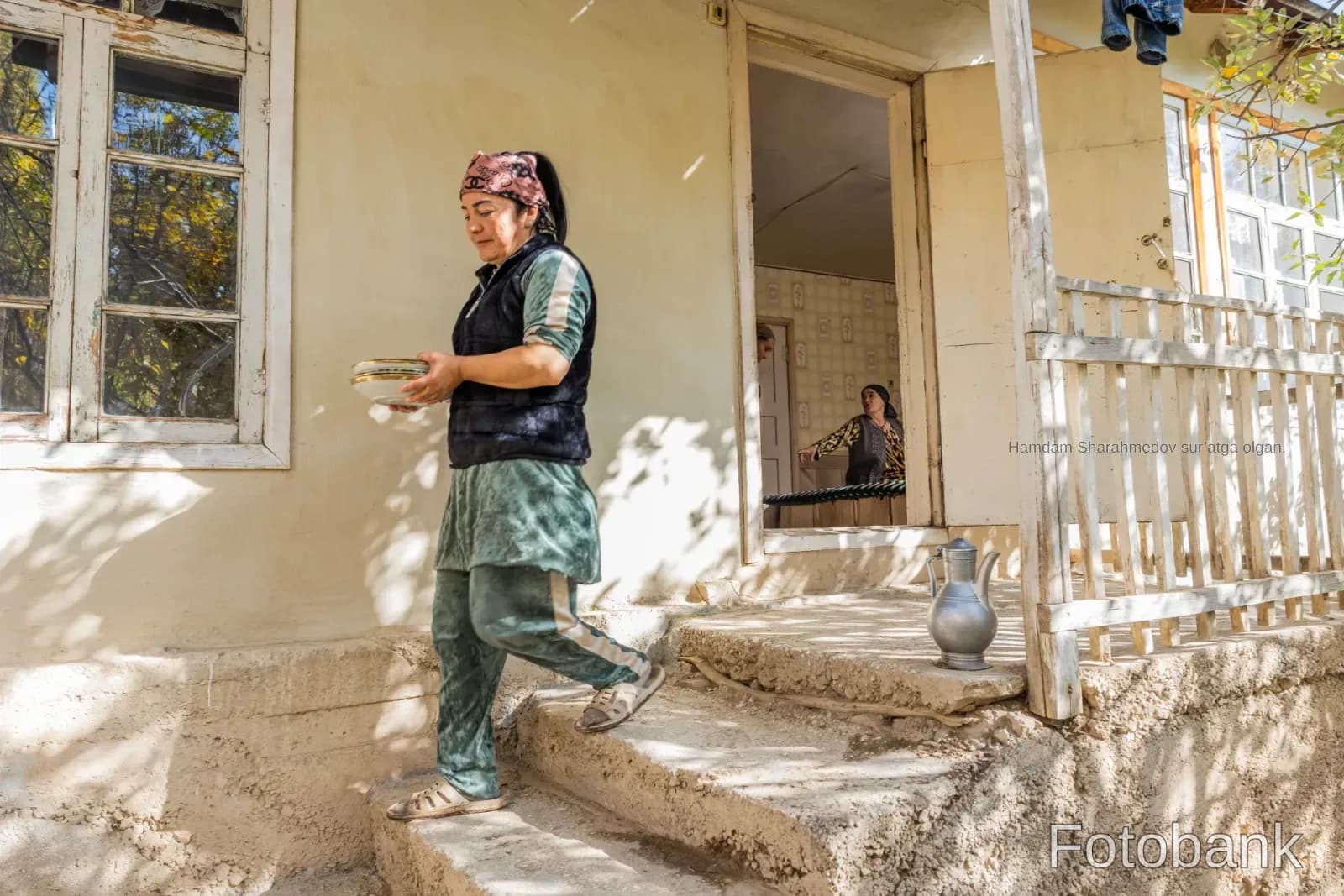 Person walking down outdoor steps carrying plates near a house