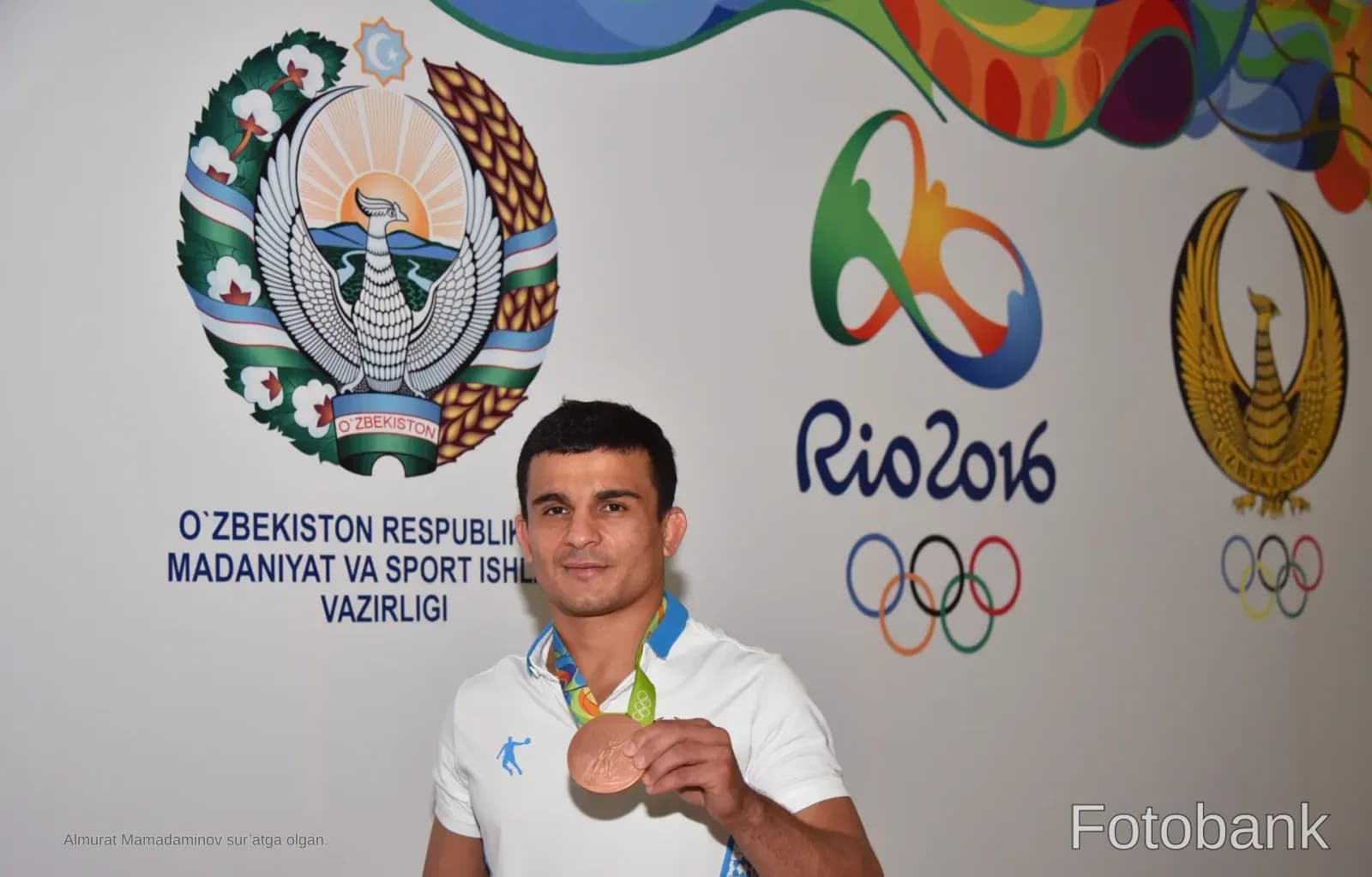 Athlete holding a medal in front of official emblems