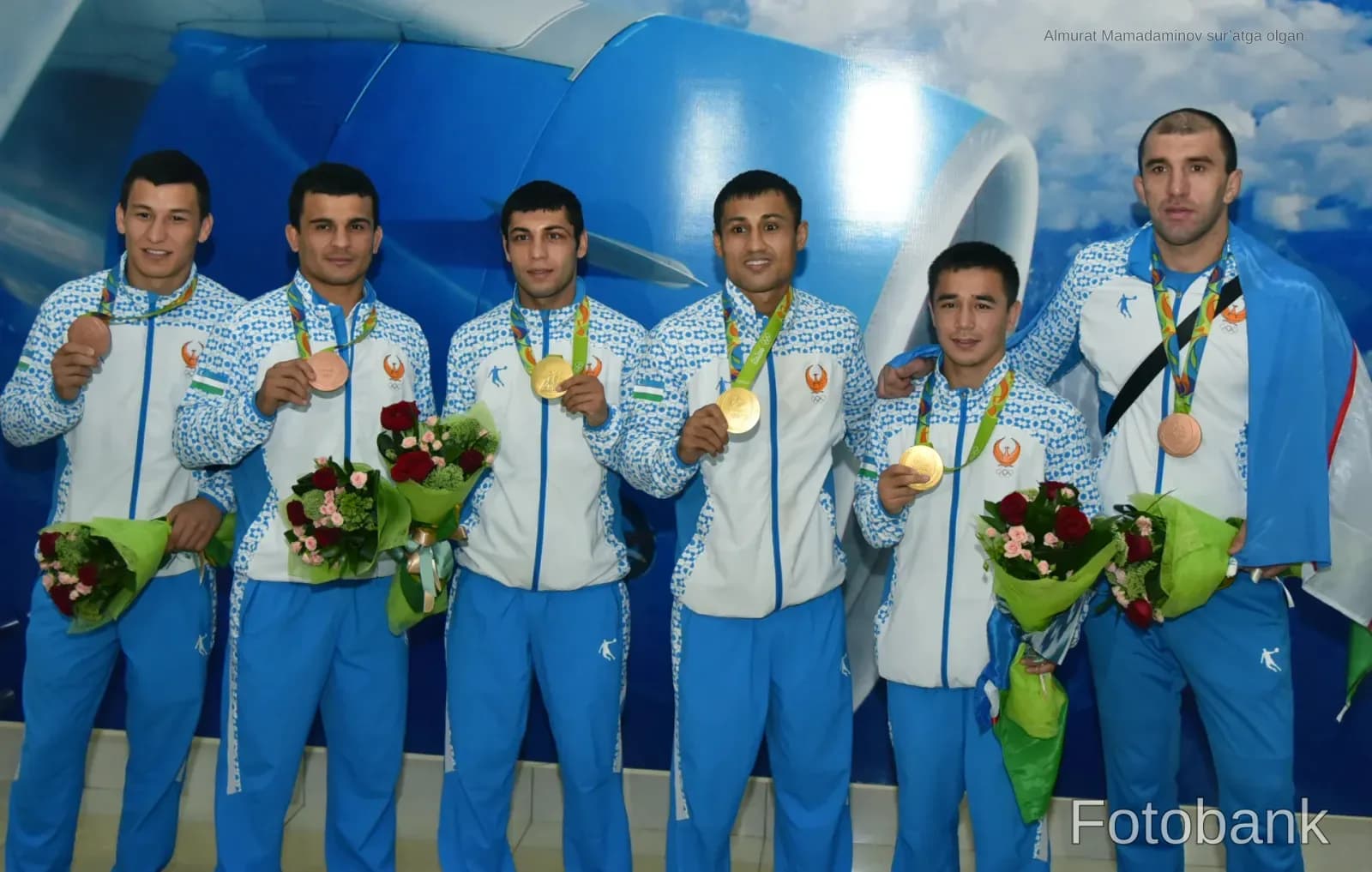 Athletes wearing medals and holding bouquets