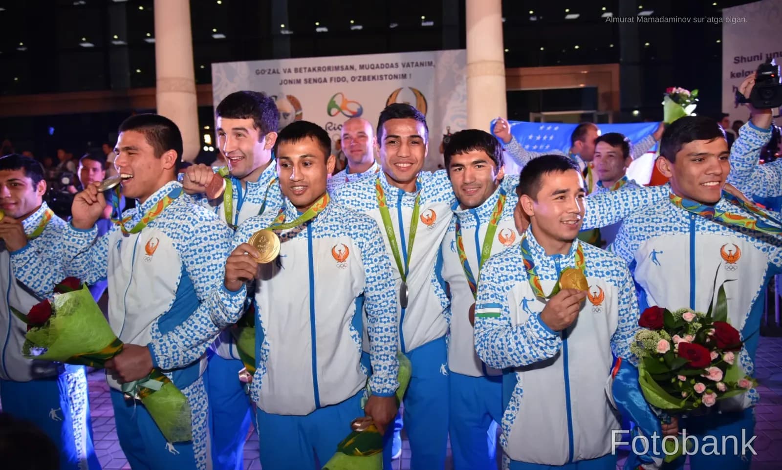 Athletes in matching tracksuits holding medals