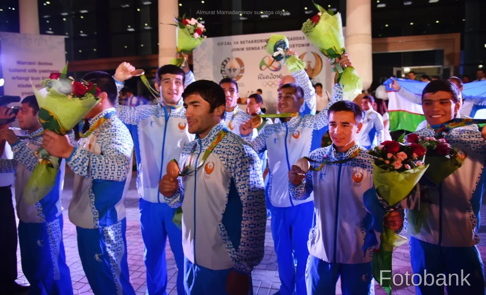 Group of athletes wearing medals and holding bouquets