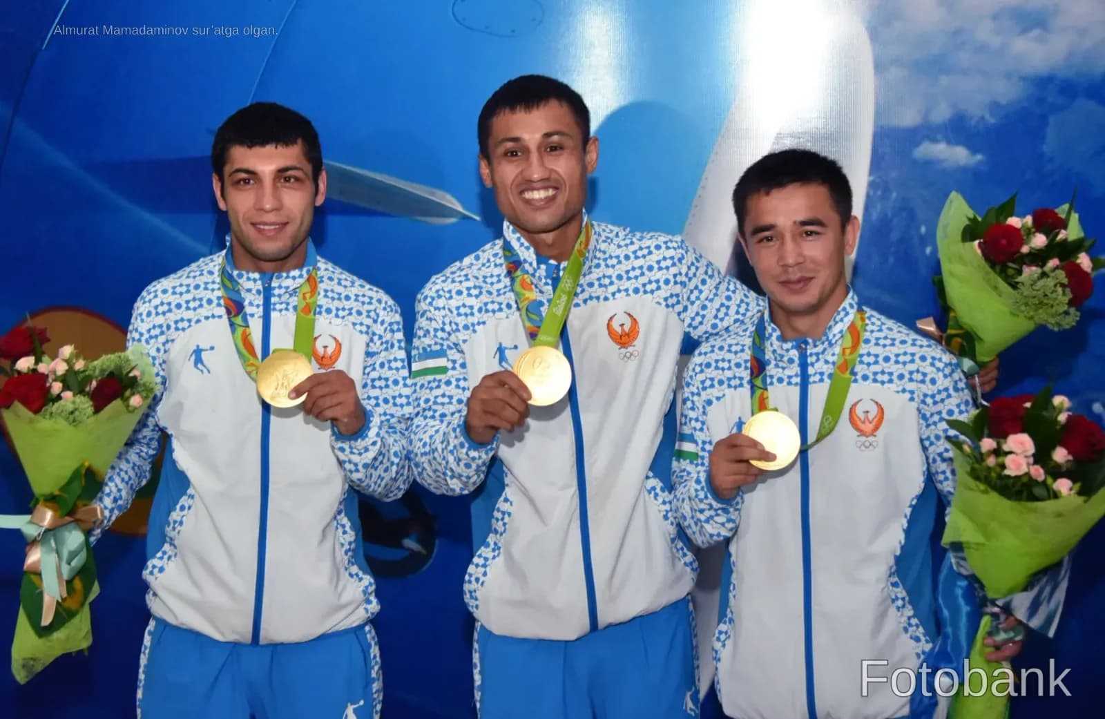 Three athletes wearing medals and holding bouquets