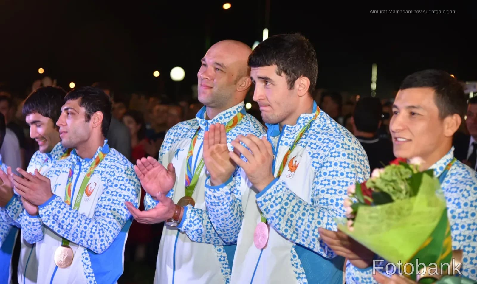 Athletes in matching patterned jackets applauding outdoors
