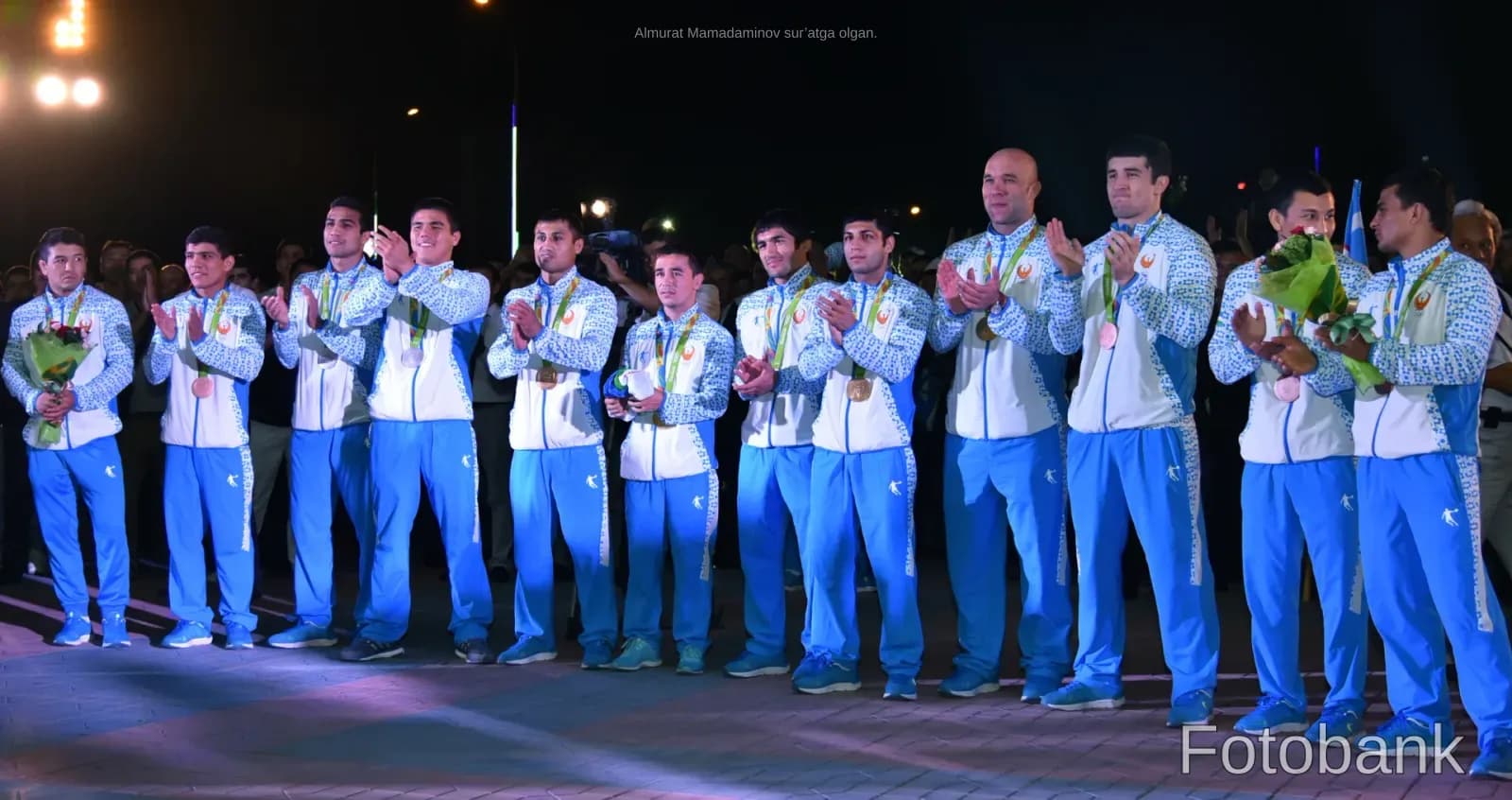 Athletes in matching tracksuits clapping during an event
