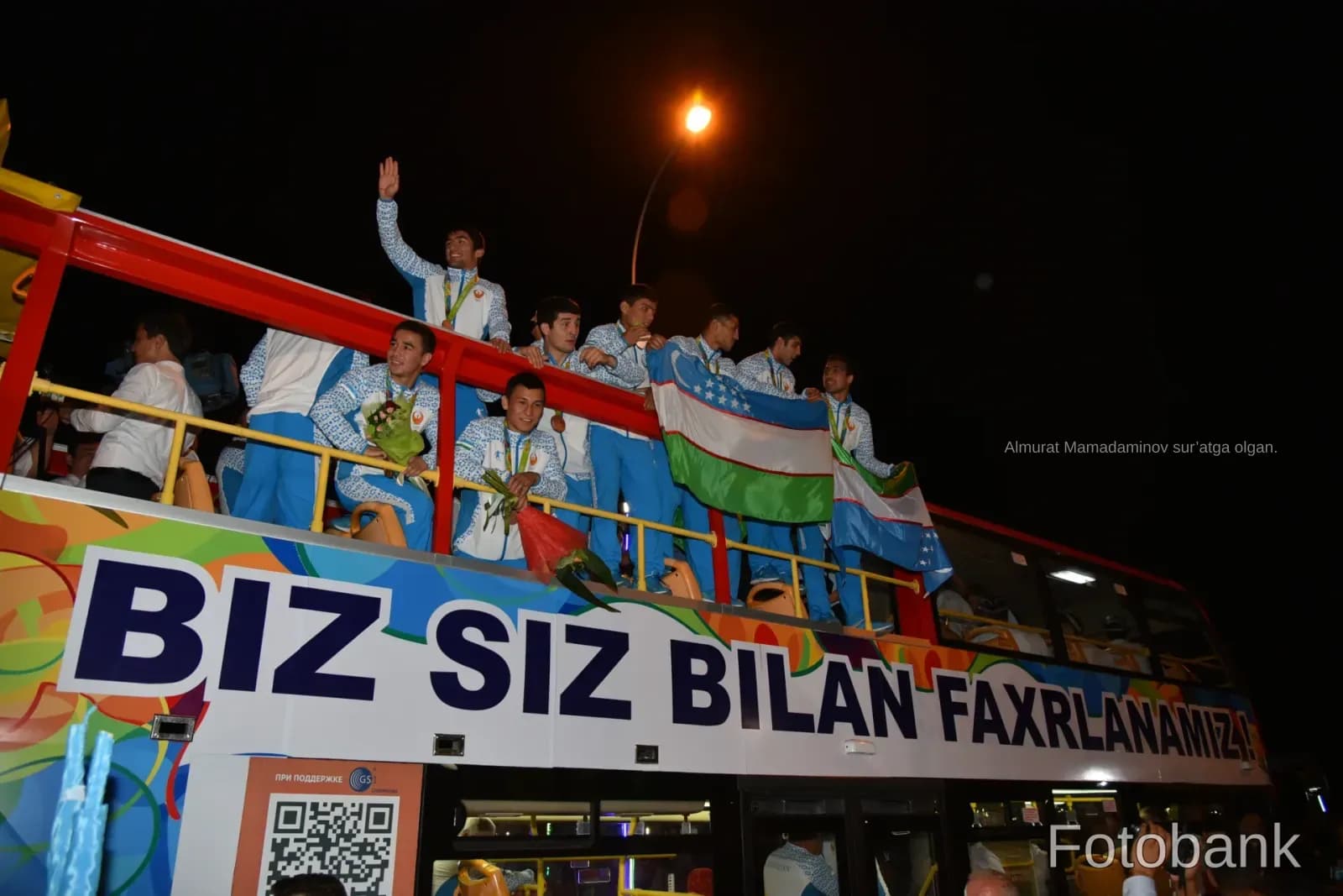 Group of athletes riding on top of a bus at night