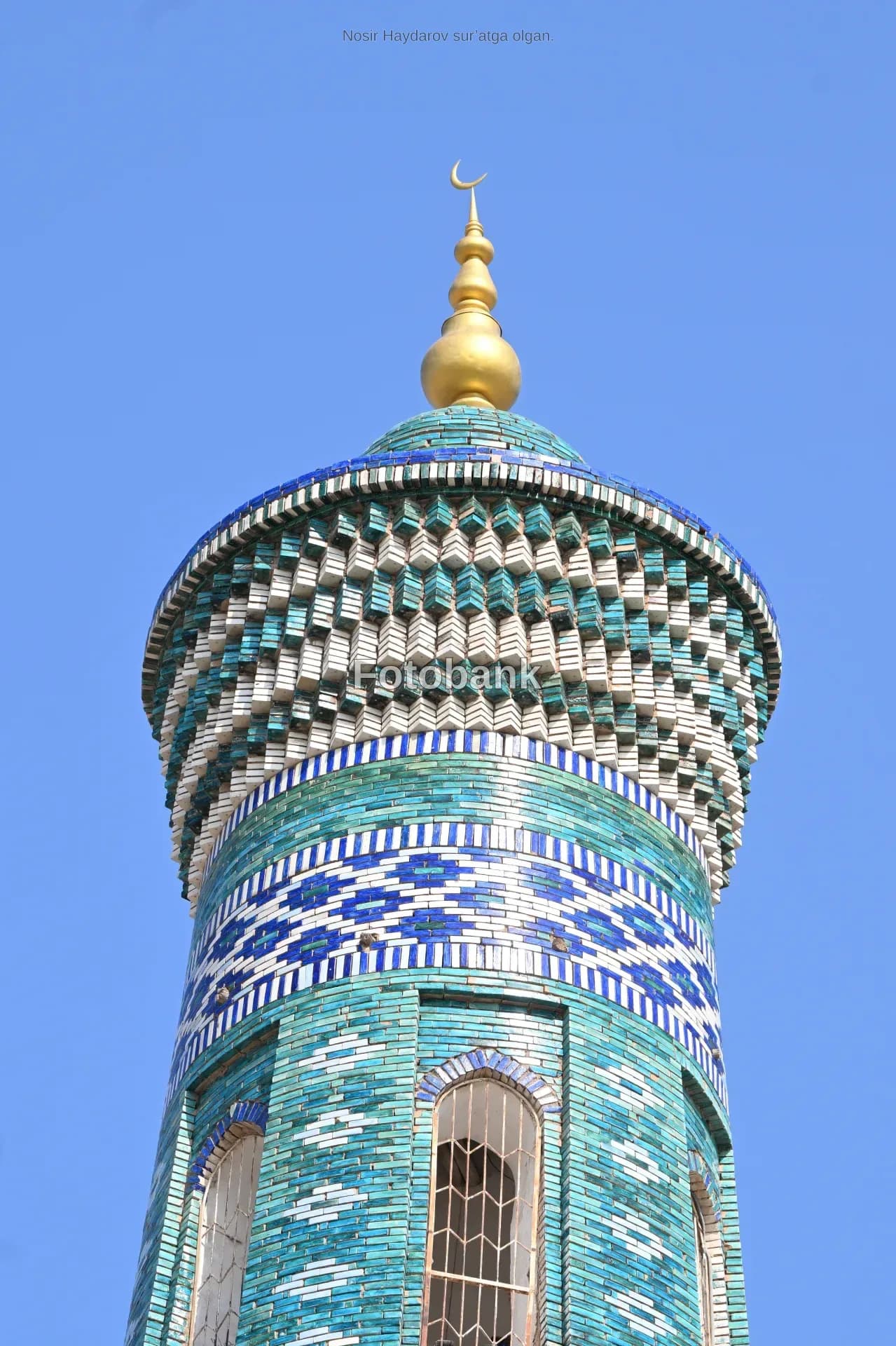 Detailed view of an ornate minaret tower adorned with blue and white tilework
