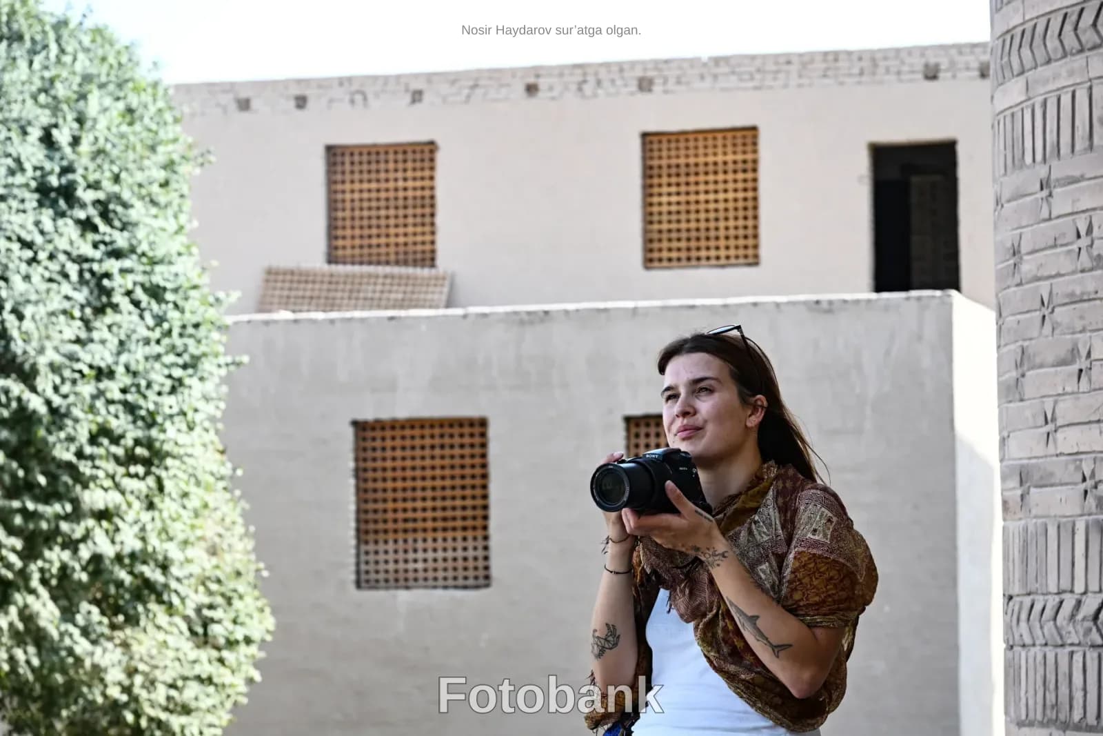 Woman holding camera outdoors near historic buildings