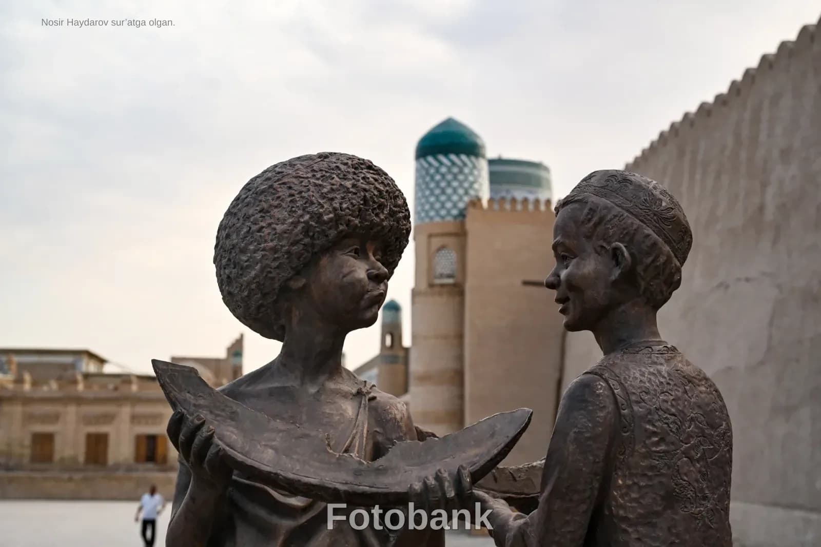 Bronze statues of figures holding a melon piece outdoors