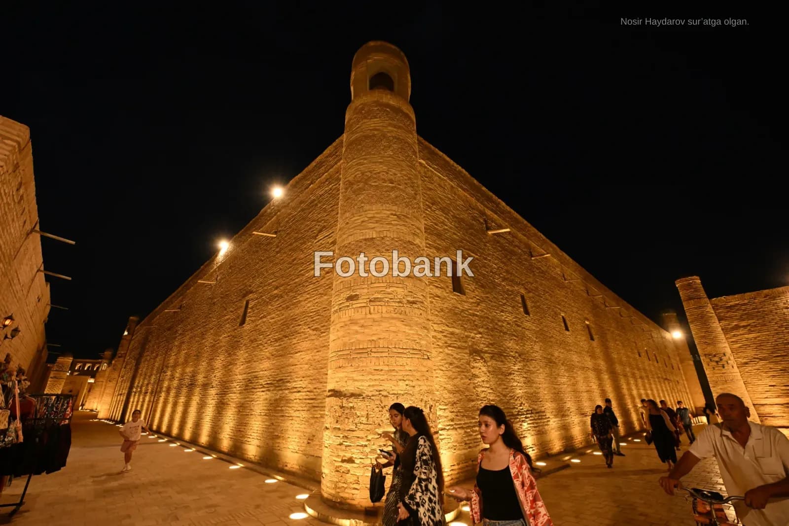 People walking by ancient brick building at night