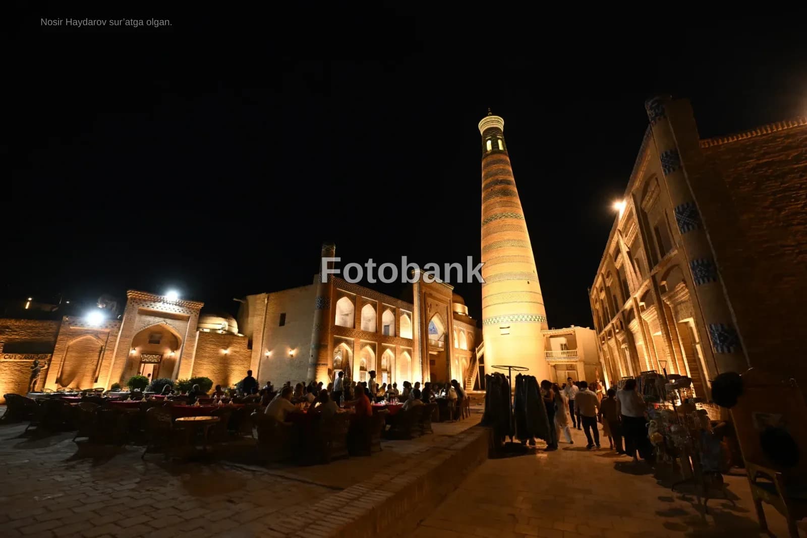 People gathered at illuminated square with historical buildings at night