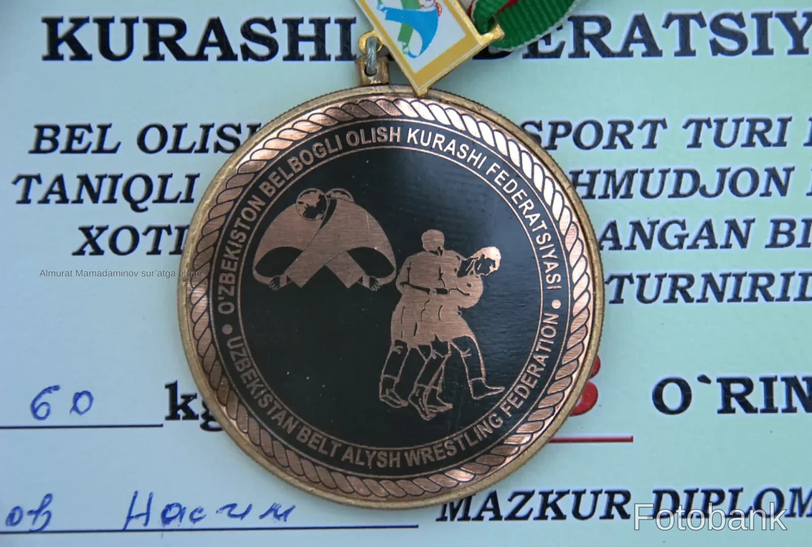 Медаль спортивного награждения с выгравированными фигурами, лежащая на документе с текстом