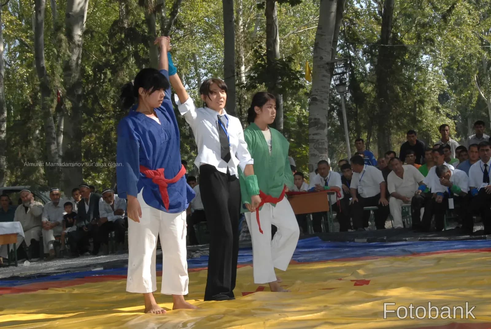 Athletes and referee on mat outdoors