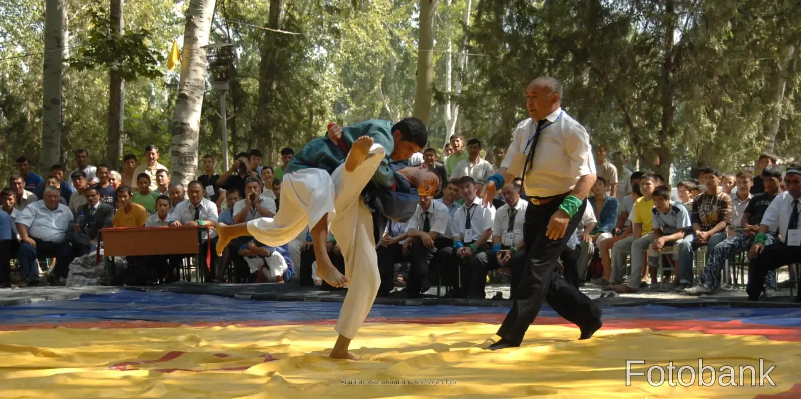 Wrestlers competing in a match on a mat outdoors