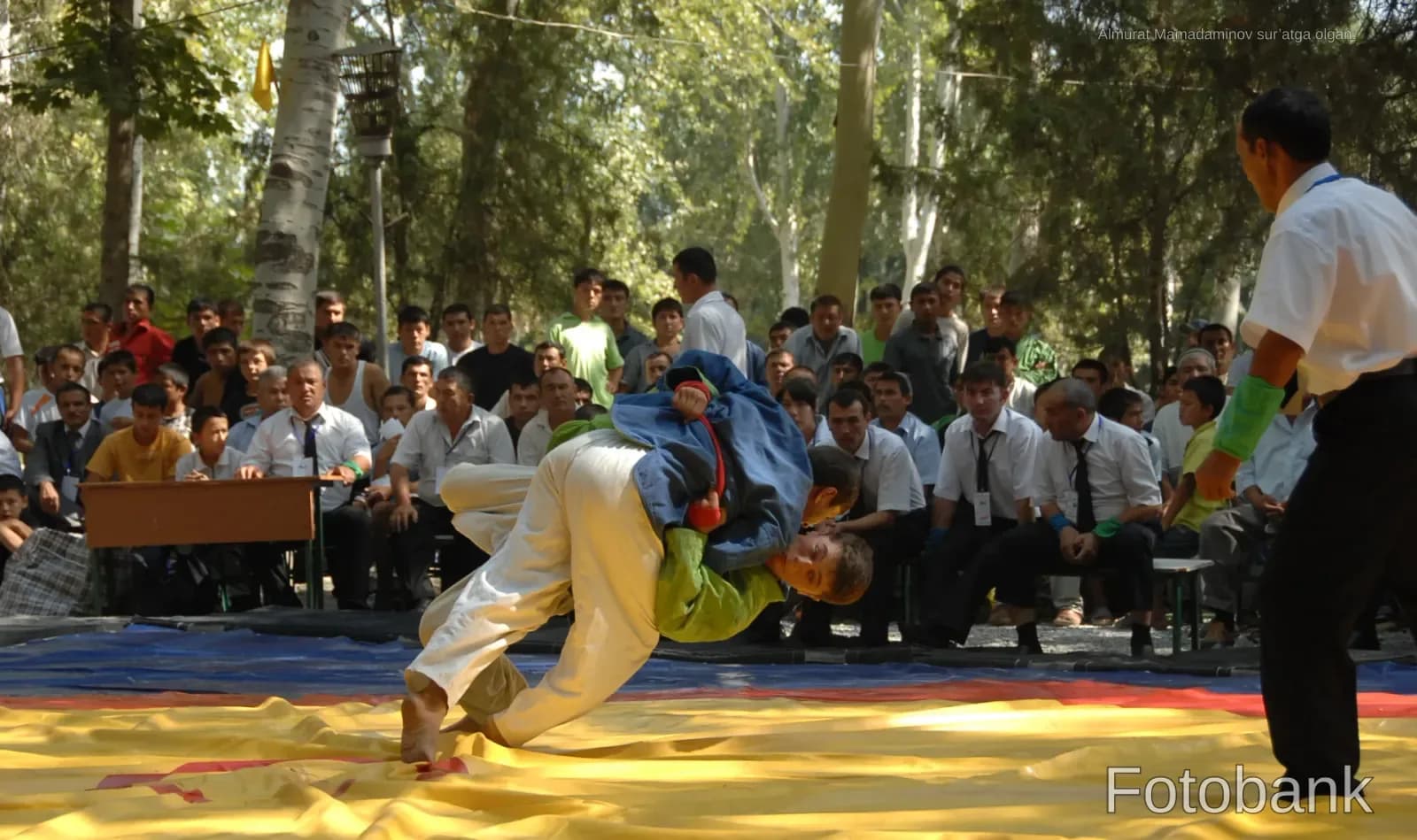 Wrestlers competing on a mat outdoors with spectators