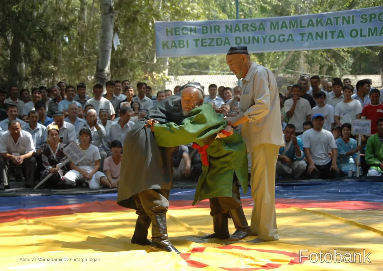 Men engage in traditional wrestling on a mat outdoors