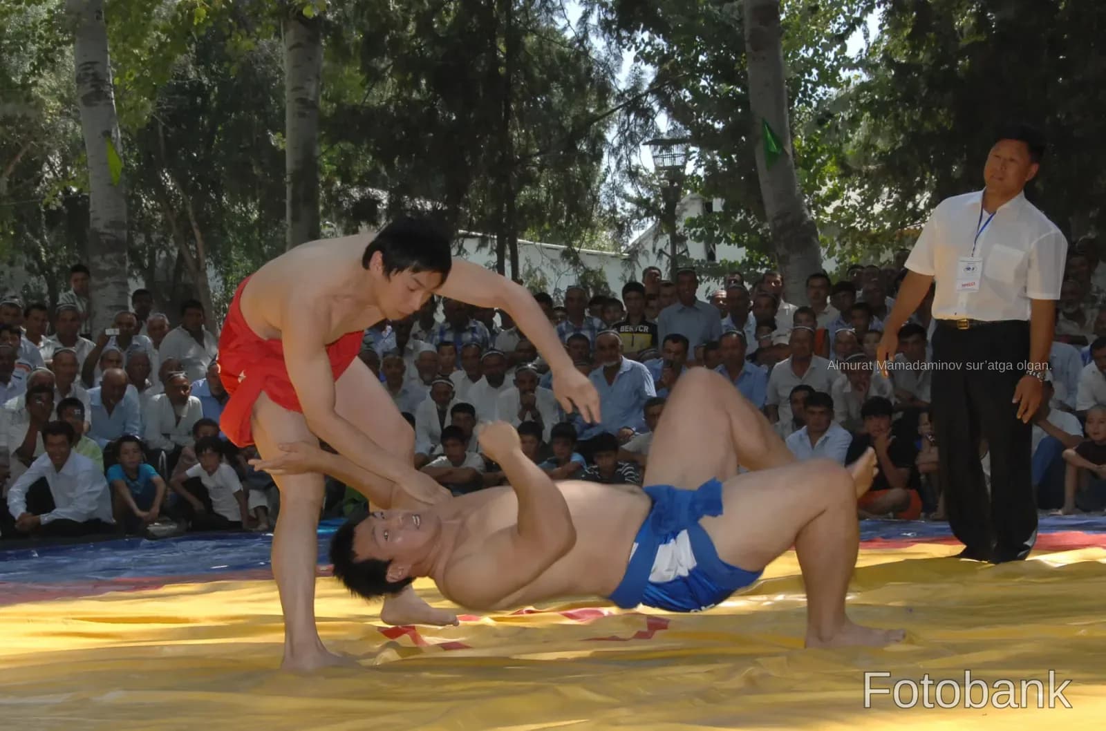 Wrestlers competing on a mat outdoors