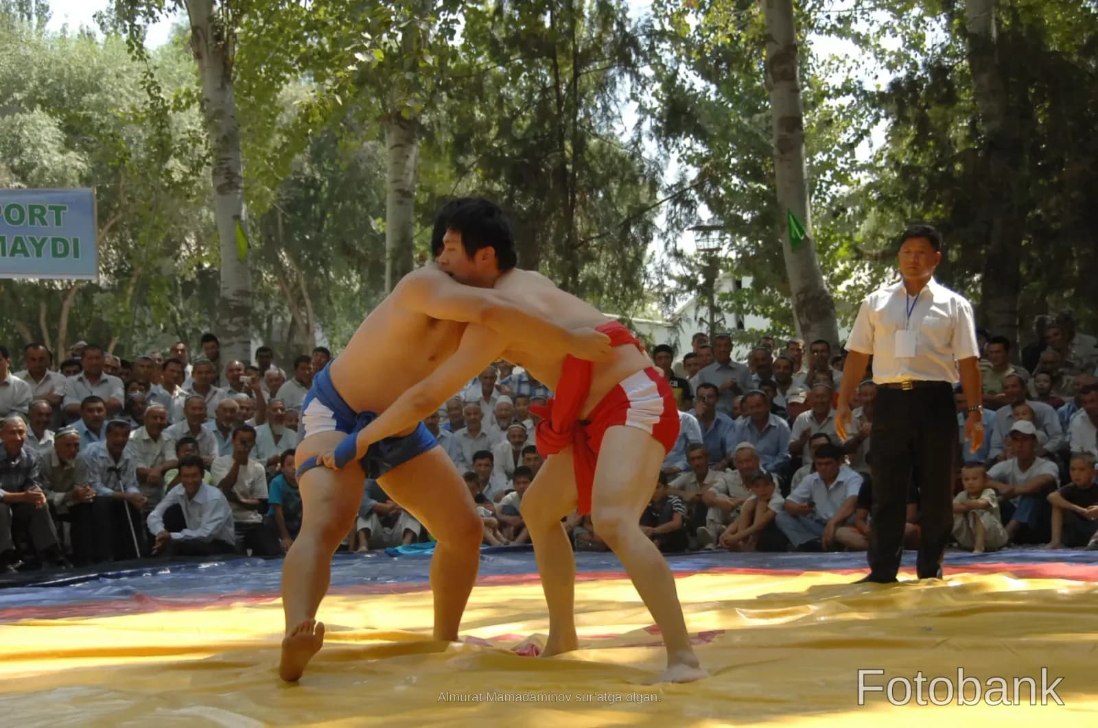 Wrestlers competing on a mat outdoors